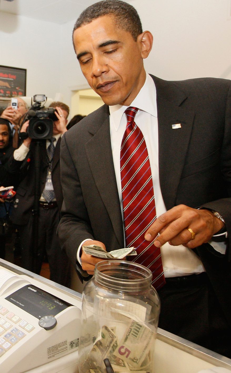 President Barack Obama drops a five dollar bill into the tip jar as he and Vice President Joe Biden, not pictured, make an unannounced visit to Ray's Hell Burger in Arlington, Va., to have lunch, Tuesday, May 5, 2009. (AP Photo/Charles Dharapak)