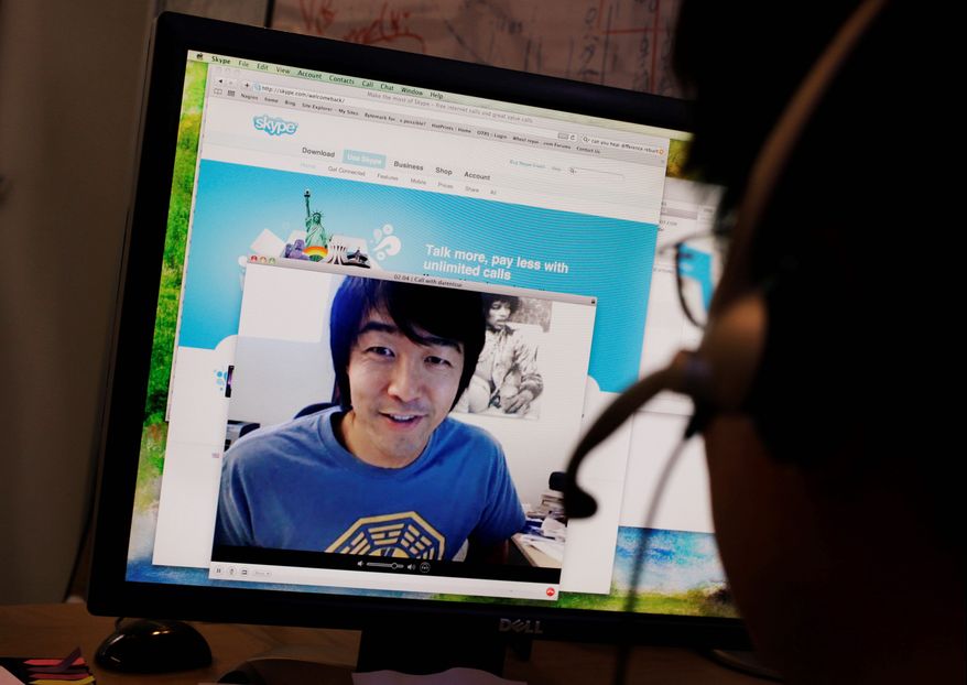 Ed Ho (right) demonstrates the online telecommunications service Skype with friend Daren Tsui, on-screen, at Mr. Ho's home in Palo Alto, Calif. (AP Photo)