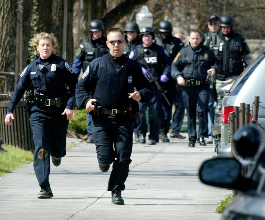 ** FILE ** Police officers run from Norris Hall on the Virginia Tech campus in Blacksburg, Va., on April 16, 2007, after the worst mass shooting in modern U.S. history. (AP Photo)