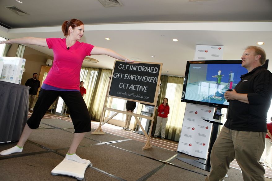 **COMMERCIAL IMAGE** In this photo provided by the American Heart Association and Nintendo of America, David Young of Nintendo, right, and mother of four Erica Maynard, of Newport News, Va., demonstrate how active-play video games like Wii Fit Plus can help consumers build a healthy lifestyle at a press event Monday, May 17, 2010 in New York. The American Heart Association and Nintendo announced today that they are joining forces to promote physically active play. (David Goldman/AP Images for American Heart Association and Nintendo of America)
