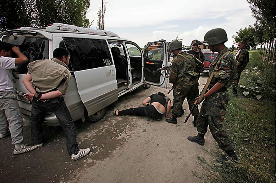 Kyrgyz soldiers and volunteers check passing cars and search passengers for weapons at a checkpoint on the Uzbek side the border near the southern Kyrgyz city of Osh on Wednesday, June 16, 2010. Heavy arms fire rang out over Osh before dawn Wednesday as authorities struggled to bring order to the country's south, which has been thrust into chaos by days of deadly ethnic riots. The violence has prompted more than 100,000 Uzbeks to flee for their lives to Uzbekistan, with tens of thousands more camped on the Kyrgyz side or stranded in a no man's land. (AP Photo/Alexander Zemlianichenko)