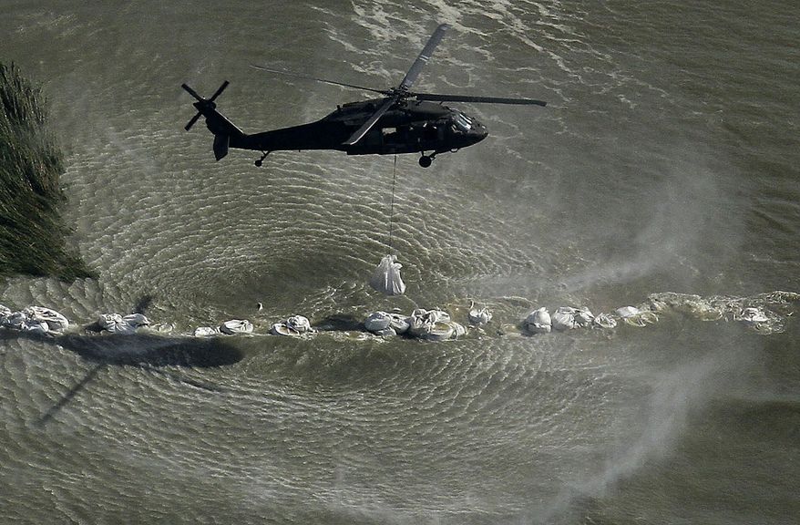 A helicopter drops bags of sand onto a barrier during efforts to contain oil from the Deepwater Horizon oil spill in Barataria Bay near Port Sulphur, La., Friday, June 25, 2010. (AP Photo/Gregory Bull)