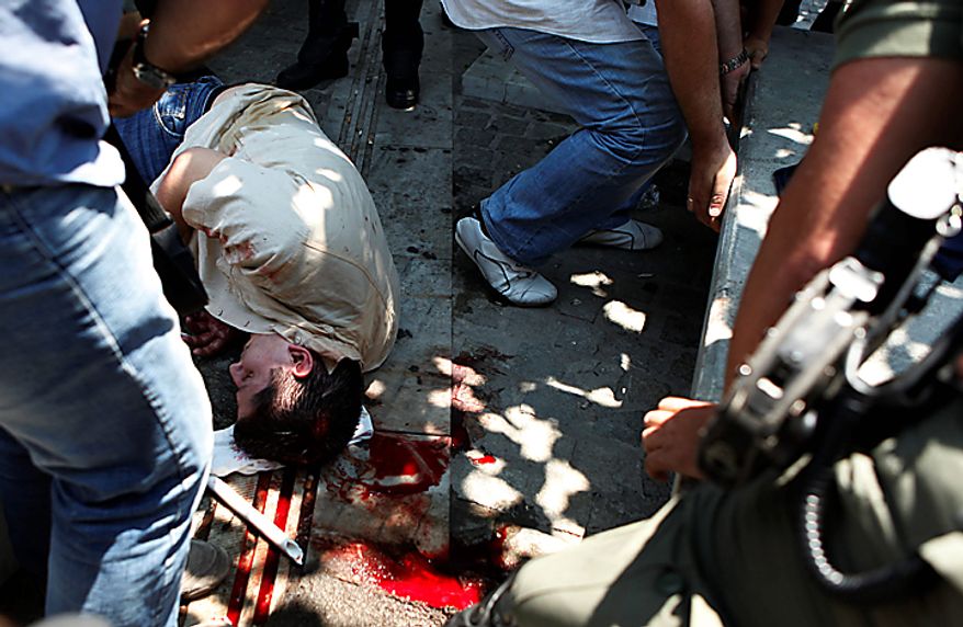 A man lies injured in the street after being assaulted by violent demonstrators during a protest in central Athens, Thursday, July 8, 2010. Authorities identified the man as a public servant who was apparently wrongly identified as a plain clothed policeman. More than 12,000 people took part in two separate protest marches, according to police estimates. Greece's governing Socialists are battling growing discontent as a new round of economic austerity faces party dissent, growing public hostility and fresh strike. (AP Photo/Evi Zoupanou)