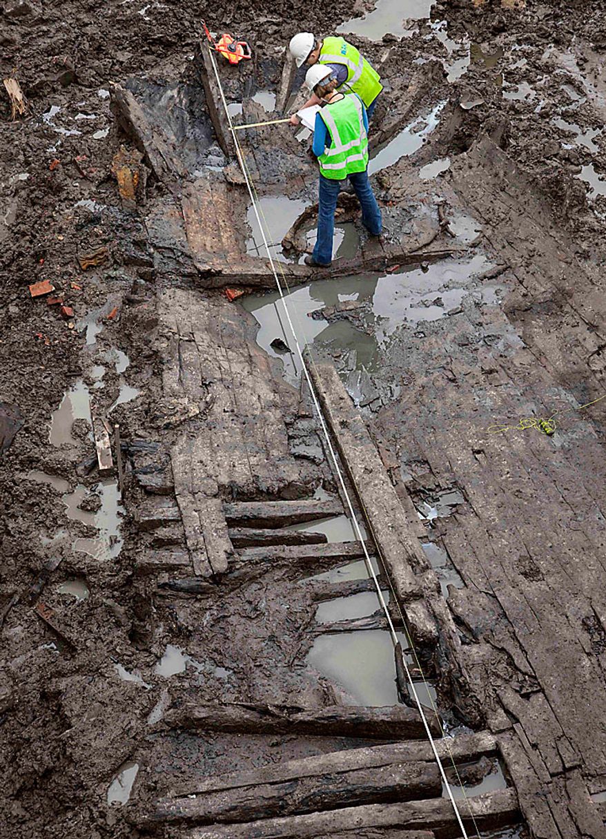 Archeologists Elizabeth Meade, top, and Molly McDonald take measurements of the wood hull of a 32-foot-long (9.75 meters) 18th century boat at the World Trade Center site on Thursday, July 15, 2010 in New York. (AP Photo/Mark Lennihan)