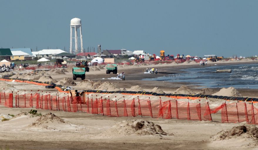 Workers clean up oil deposits from the beach on Monday, July 19, 2010, in Grand Isle, La., where petroleum from the Deepwater Horizon spill continues to wash ashore. (AP Photo/Dave Martin)