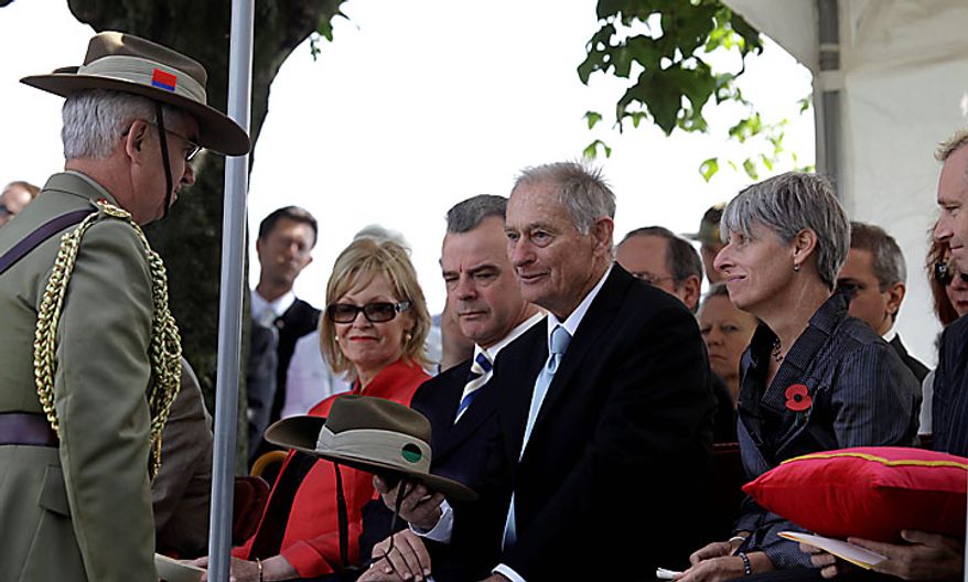 John Mather, center, receives the traditional Australian Slouch Hat during a re-burial ceremony for his uncle, Australian WWI soldier, Private Alan James Mather, at Prowse Point Cemetery in Ploegsteert, Belgium on Thursday, July 22, 2010. Mr. Mather, originally from Invernell, NSW, Australia was one of 216,000 men from Australia, New Zealand and the UK who fought in the Battle of Messines from June 7-14, 1917. (AP Photo/Virginia Mayo)