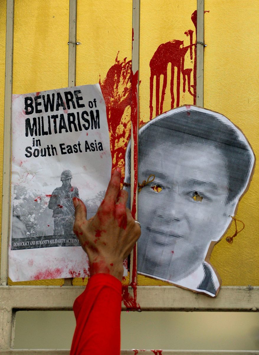 An Indonesian activist puts a poster next to a mask of Mr. Abhisit on the gate of the Thai Embassy during a protest against the military crackdown against Red Shirts in Bangkok. (Associated Press)