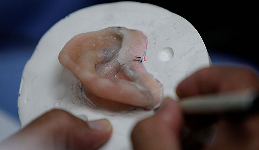 In this photo taken June 23, 2010, Dr. Joe Villalobos works on an artificial ear for Master Sgt. Todd Nelson in in a facial prosthetics lab in San Antonio. (AP Photo/Eric Gay)