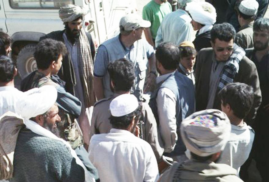Tom Little (top center in blue shirt with baseball cap), an optometrist and team leader with the International Assistance Mission, joins villagers and other team members in Afghanistan in this undated photo. (AP Photo/Provided by David L. Evans)