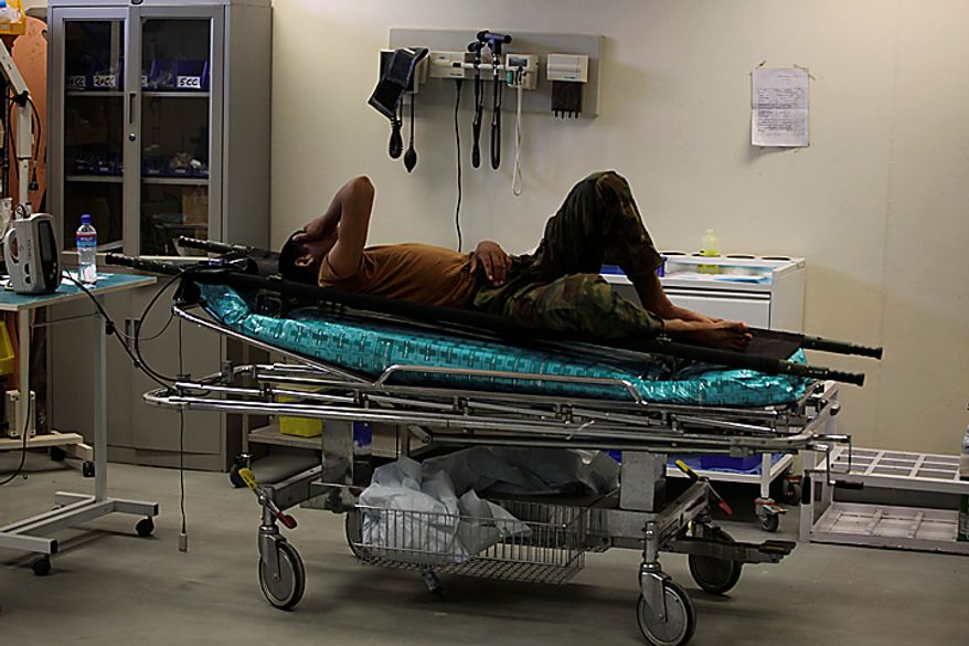 In this Saturday, Aug. 7, 2010 photo, a wounded Afghan army soldier lis on a stretcher waiting to be seen, while more serious cases are attended to, inside the ER at Kandahar Regional Military Hospital, KRMH, inside Camp Hero, Kandahar province, southern Afghanistan. A U.S Air Force Medical Training Advisory Group, or MTAG team, comprised of 12 medical professionals, is assigned to the Afghan military hospital, and are tasked with providing transitional guidance to local medical workers, who treat Afghan soldiers, civilians, and occasionally insurgents. (AP Photo/Brennan Linsley)