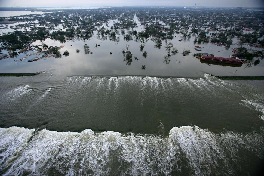 In this Aug. 30, 2005, picture, floodwaters from Hurricane Katrina pour through a levee along Inner Harbor Navigaional Canal near downtown New Orleans, a day after Katrina passed through the city. (AP Photo/Pool, Vincent Laforet)