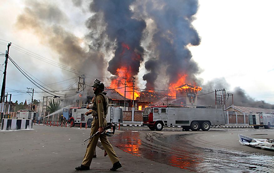 A policeman patrols as flames rise from a government building set on fire by protesters in Srinagar, India, Saturday, Sept. 11, 2010. Police fired warning shots and tear gas to disperse hundreds of demonstrators who attacked a police post and burned government offices in Kashmir on Saturday, as tens of thousands of people took to the streets to protest Indian rule in the Himalayan region, officials said. (AP Photo/Altaf Qadri)
