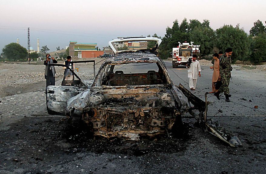 An Afghan soldier and locals walk by a site after a suicide car-bomb exploded in Behsood district of Jalalabad, Afghanistan, Monday Sept. 20, 2010. The attack on a NATO convoy reportedly injured four Afghan civilians. (AP Photo/Rahmat Gul)