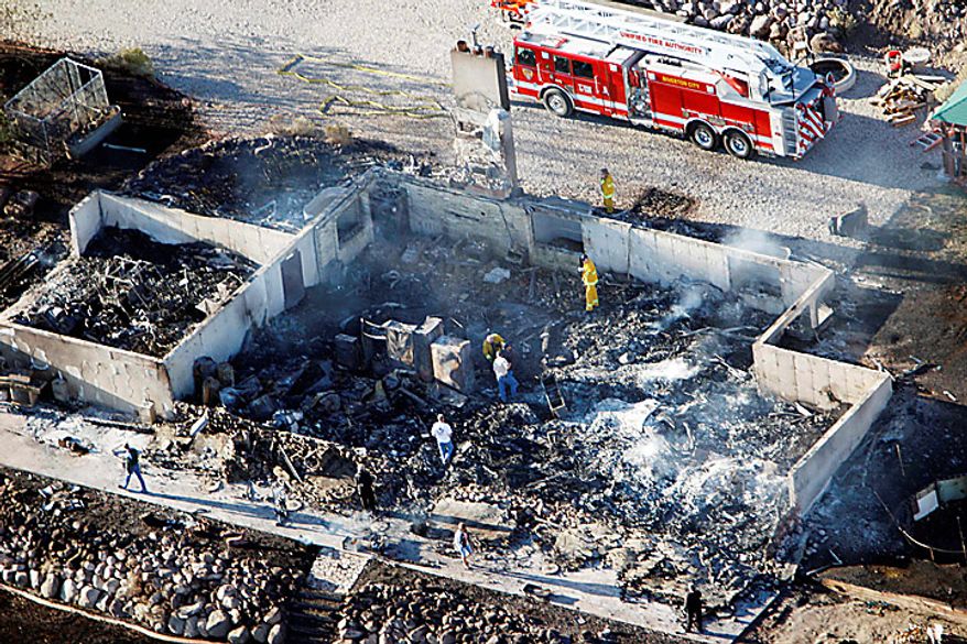 Home owners and fire crews sift through the remnants of a home that was destroyed by the fire in Herriman, Utah on Monday, Sept. 20, 2010. A wind-stoked wildfire sparked at a firing range during a National Guard training session blazed across thousands of acres Monday as crews rushed to keep it from burning more than four homes that were destroyed overnight. The fire moved back on itself Monday as the Utah National Guard acknowledged it wasn't the first time that live-fire exercises had sparked a fire at Camp Williams, a sprawling compound 30 miles south of Salt Lake City. (AP Photo/Scott G Winterton, Pool)