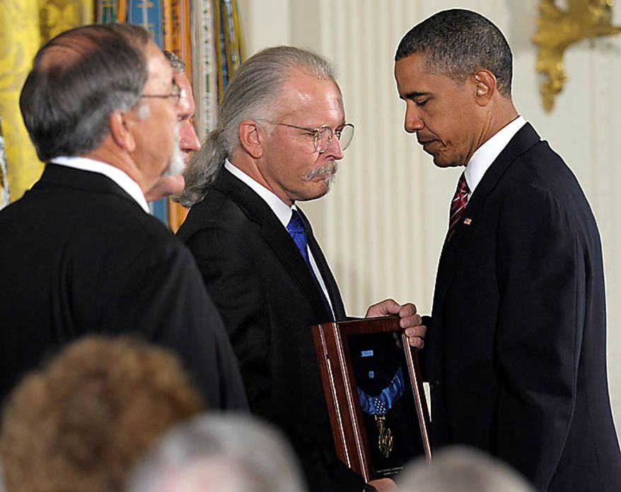 President Barack Obama presents the Medal of Honor posthumously to the sons of Air Force Chief Master Sgt. Richard L. Etchberger, from right, Richard Etchberger, Corey Etchberger, and step son Steve Wilson , Tuesday, Sept. 21, 2010, during a ceremony in the East Room of the White House in Washington. Etchberger received the honor for his heroic actions in combat in Laos on March 11, 1968, after deliberately exposing himself to enemy fire in order to put his wounded comrades in rescue slings permitting them to be airlifted to safety. (AP Photo/Susan Walsh)