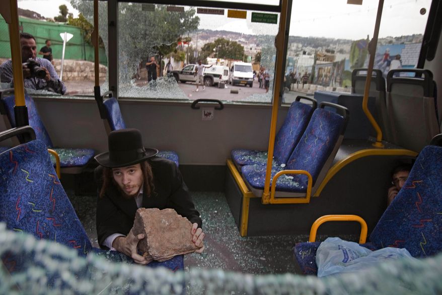 Two ultra-Orthodox Jewish men protect themselves inside a bus from Palestinian rioters outside Jerusalem's Old City on Wednesday, Sept. 22, 2010. Violence erupted after a 32-year-old Palestinian laborer was killed by a private security guard watching over Jewish families in the Silwan neighborhood in east Jerusalem. During the man's funeral, a mob of protesters set tires on fire, smashed the windows of several buses and called for revenge. (AP Photo/Bernat Armangue)