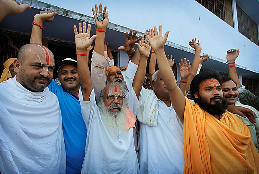 Hindu priests celebrate after hearing the first reports on the court verdict in Ayodhya, India, Thursday, Sept. 30, 2010. An Indian court ruled Thursday that a disputed holy site that has sparked bloody communal riots across the country in the past should be divided between the Hindu and Muslim communities. However, the court gave the Hindu community control over the section where the now demolished Babri Mosque stood and where a small makeshift tent-shrine to the Hindu god Rama rests. While both Muslim and Hindu lawyers vowed to appeal to the Supreme Court, the compromise ruling seemed unlikely to set off a new round of violence, as the government had feared. (AP Photo/Rajesh Kumar Singh)
