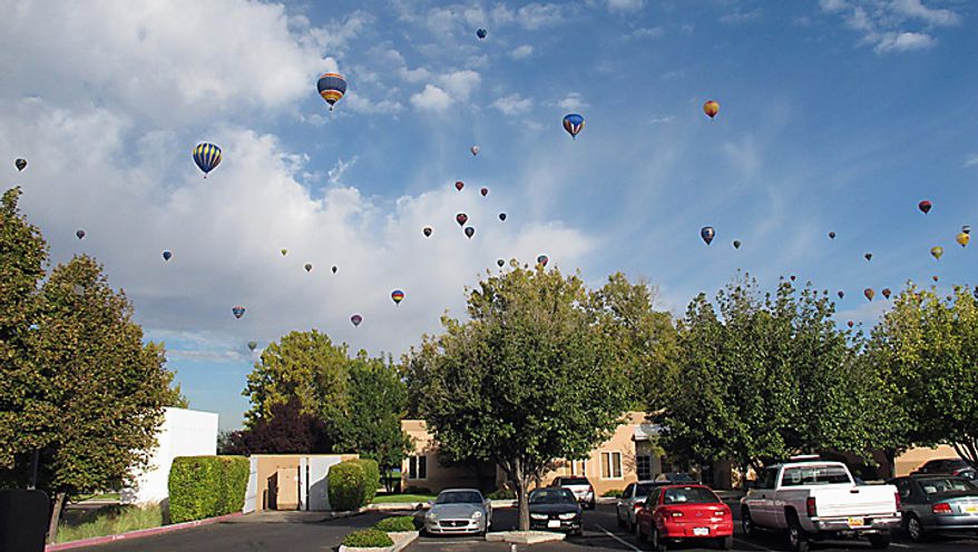 Hot air balloons fill the skies over an office complex in Albuquerque, N.M., on the third day of the Albuquerque International Balloon Fiesta Monday, Oct. 4, 2010. (AP Photo/Tim Korte)