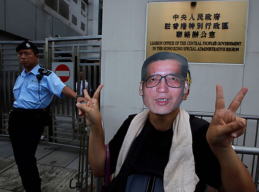 A pro-democracy protester gestures while wearing a mask of Chinese dissident Liu Xiaobo as he and others demand Liu's release outside China's Liaison Office in Hong Kong Monday, Oct. 11, 2010. The imprisoned Chinese dissident who won this year's Nobel Peace Prize was allowed to meet with his wife and told her in tears that he was dedicating the award to victims of a 1989 military crackdown on pro-democracy protesters, his wife and a close friend said. (AP Photo/Kin Cheung)