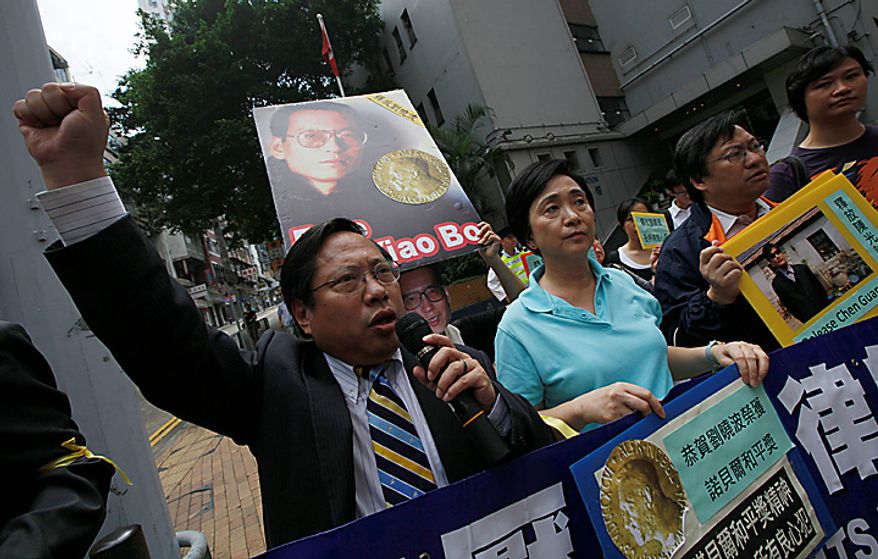 Pro-democracy protesters carry pictures of Chinese dissident Liu Xiaobo as they demand his release outside China's Liaison Office in Hong Kong Monday, Oct. 11, 2010. The imprisoned Chinese dissident who won this year's Nobel Peace Prize was allowed to meet with his wife and told her in tears that he was dedicating the award to victims of a 1989 military crackdown on pro-democracy protesters, his wife and a close friend said. (AP Photo/Kin Cheung)
