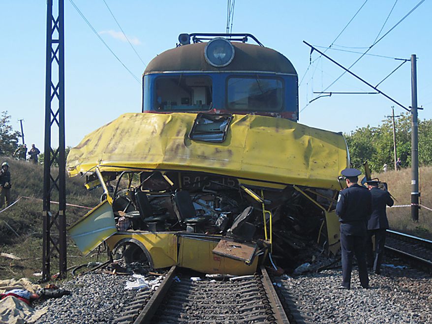 The remains of a bus lay next to a railway train at the site of an accident outside the town of Marhanets, Ukraine, Tuesday, Oct. 12, 2010. The crowded passenger bus collided with a train in eastern Ukraine Tuesday, killing 40 people and leaving 11 in critical condition, police said. The Interior Ministry said that the collision occurred outside the town of Marhanets in the Dnipropetrovsk region after the bus attempted to cross the track, ignoring a siren that indicated an oncoming train. Thirty-seven people from the bus died on the spot and another person died later in the hospital. There were no injuries reported on the train.(AP Photo/Emergency Situations Ministry)