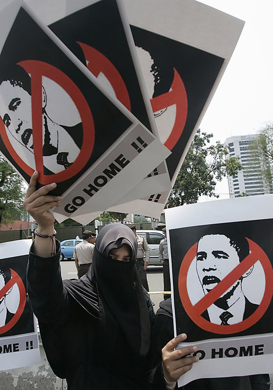 An Indonesian Muslim woman holds posters during a protest against the planned visit of U.S. President Barack Obama in front of the U.S. Embassy in Jakarta, Indonesia on Tuesday, Nov. 9, 2010. (AP Photo/Irwin Ferdiansyah)