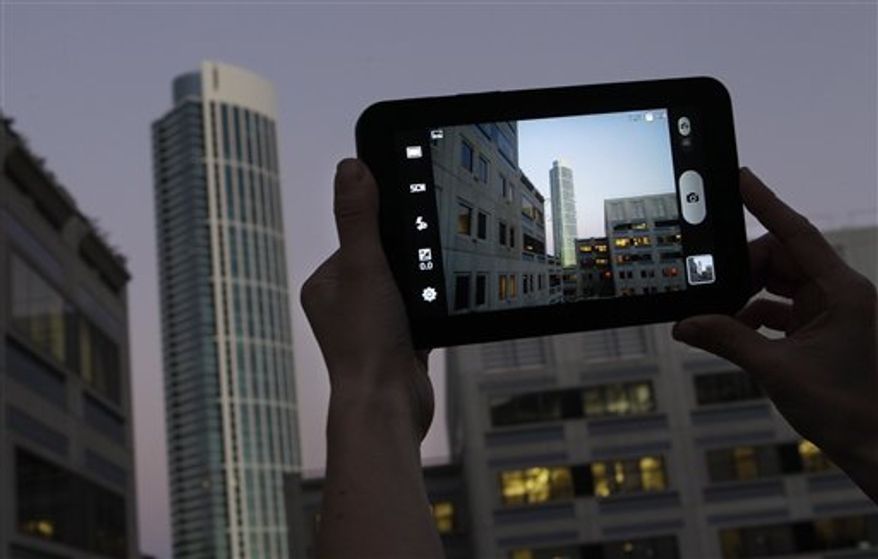 An Associated Press reporter demonstrates the Samsung Galaxy Tab during a product review in San Francisco, Tuesday, Nov. 16, 2010. (AP Photo/Jeff Chiu)