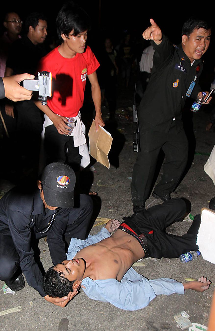 An injured Cambodian is helped by a police officer after a stampede onto a bridge at an accident site during the last day of celebrations of the water festival in Phnom Penh, Cambodia, Monday, Nov. 22, 2010. Thousands of people celebrating a water festival on a small island in a Cambodian river stampeded Monday evening, killing many people, a hospital official said. Hundreds more were hurt as the crowd panicked and pushed over the bridge to the mainland. (AP Photo/Heng Sinith)