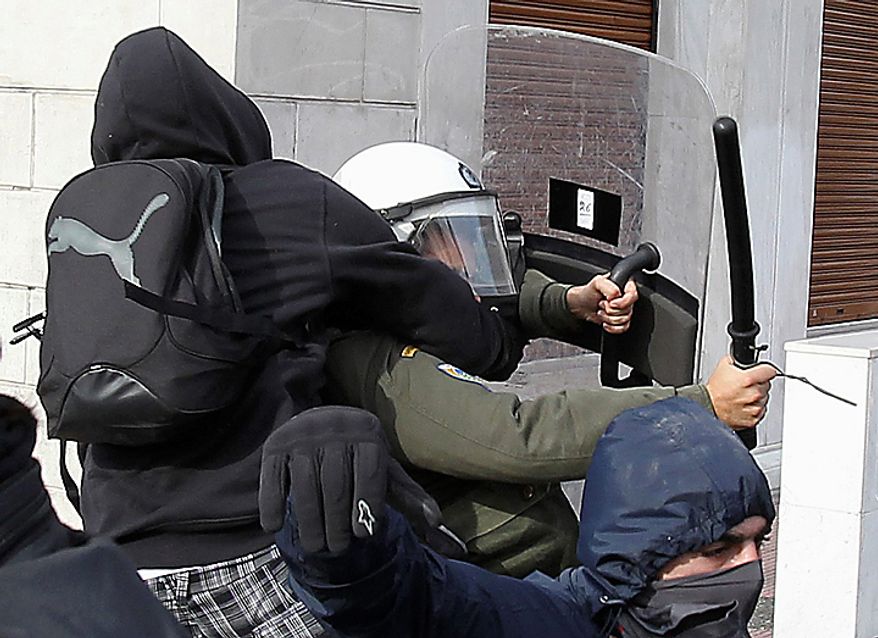 A youth with a bag attacks a riot policeman during a rally in Athens on Monday, Dec. 6, 2010. Youths hurled rocks and oranges at a government building in central Athens during a student protest to mark two years since the fatal police shooting of a teenage boy that sparked Greece's worst riots in decades. Police closed roads and deployed several thousand officers around the city but maintained a minimal presence at the site where some 1,500 students gathered outside Athens University's main buildings. (AP Photo/Thanassis Stavrakis)