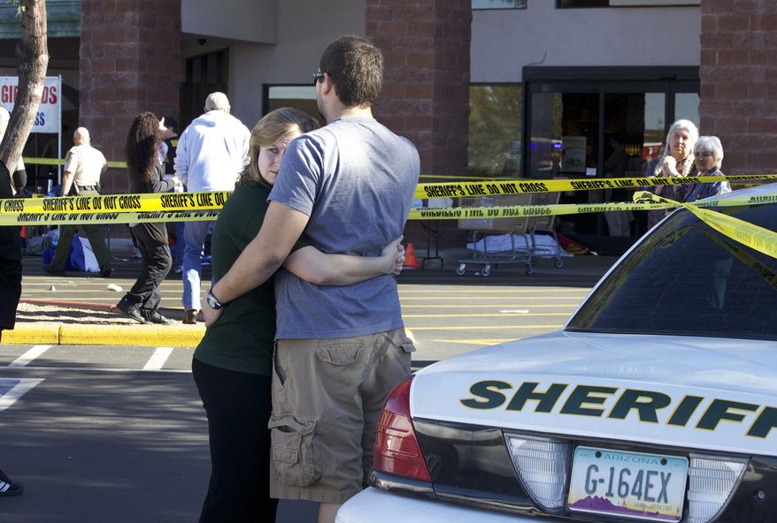 Two people embrace each other Saturday at the scene where Rep. Gabrielle Giffords, Arizona Democrat, and others were shotoutside a Safeway grocery store in Tucson, Ariz. (Associated Press)