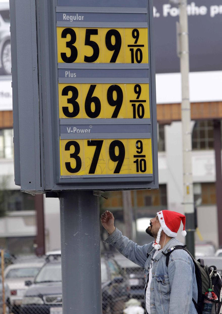 **FILE** In a Dec. 6 photo, a man with a Santa cap looks up at a marquee with high gas prices at a Shell gas station in San Francisco. (Associated Press)
