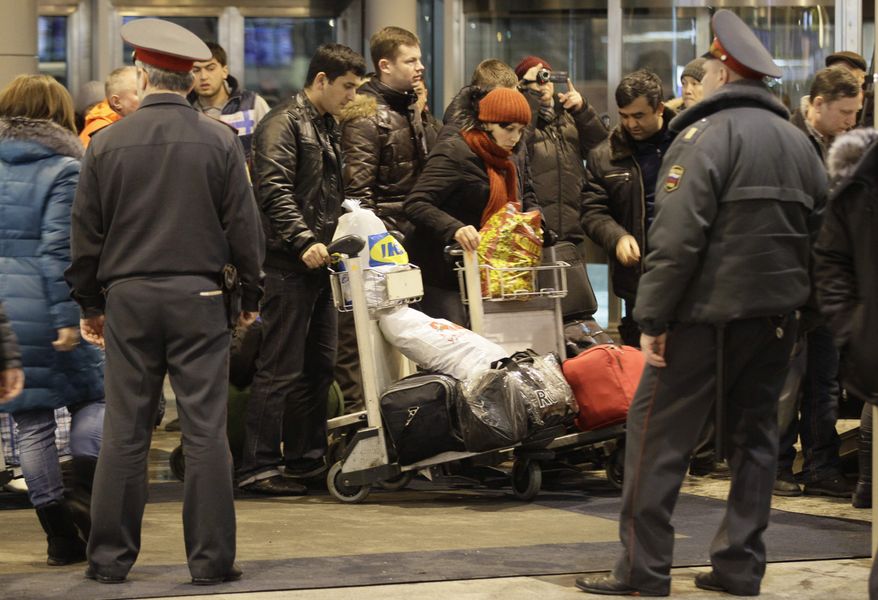 Police officers watch passengers at Domodedovo Airport in Moscow on Monday, Jan. 24, 2011, after an explosion ripped through the airport's arrivals hall. (AP Photo/Ivan Sekretarev)