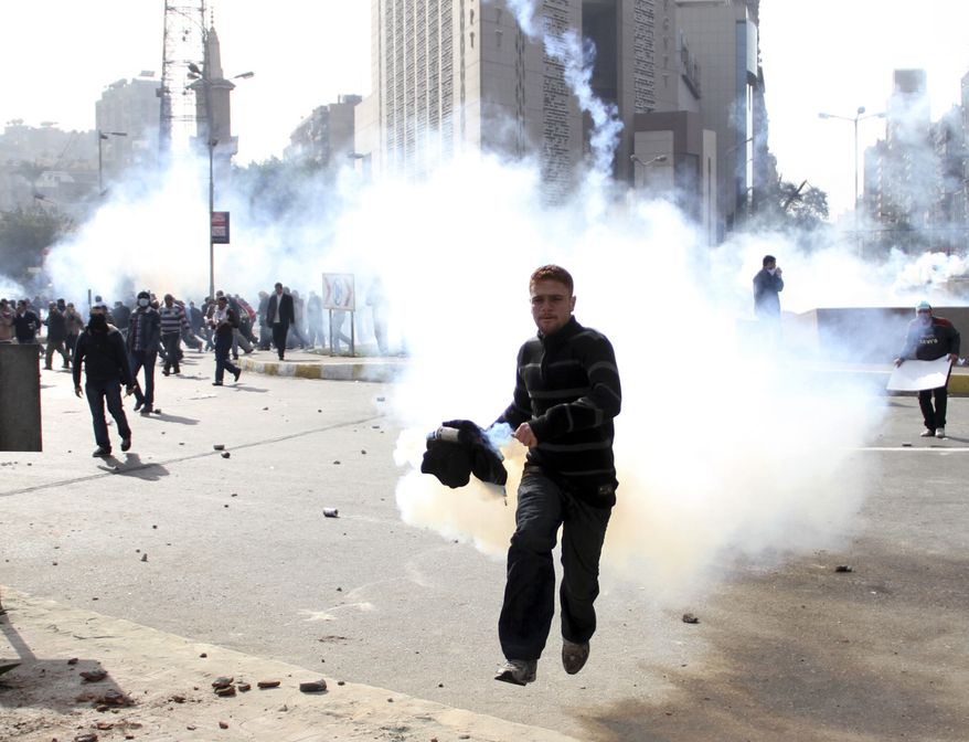 An Egyptian protester flees as anti-riot policemen fire tear gas in Cairo Friday, Jan. 28, 2011. The Egyptian capital Cairo was the scene of violent chaos Friday, when tens of thousands of anti-government protesters stoned and confronted police, who fired back with rubber bullets, tear gas and water cannons. It was a major escalation in what was already the biggest challenge to authoritarian President Hosni Mubarak's 30 year-rule. (AP Photo/Ahmed Ali)