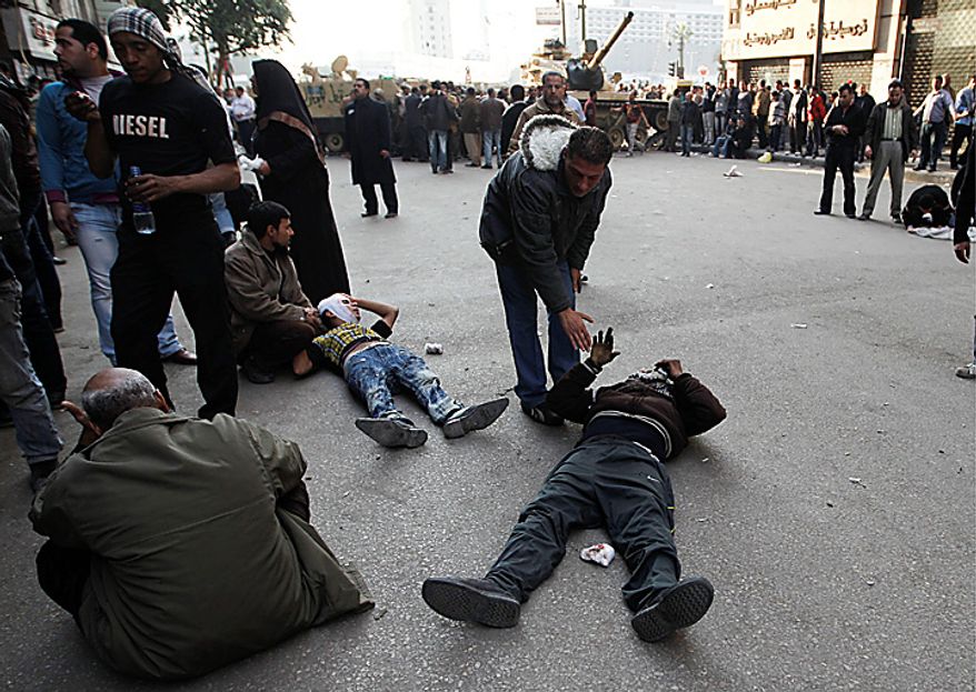 Injured anti-government protesters lie on the ground near army vehicles as they wait to be treated by medics during clashes in Tahrir, or Liberation, Square, in Cairo, Egypt, Wednesday, Feb. 2, 2011. Several thousand supporters of President Hosni Mubarak, including some riding horses and camels and wielding whips, clashed with anti-government protesters Wednesday as Egypt's upheaval took a dangerous new turn. (AP Photo/Tara Todras-Whitehill)