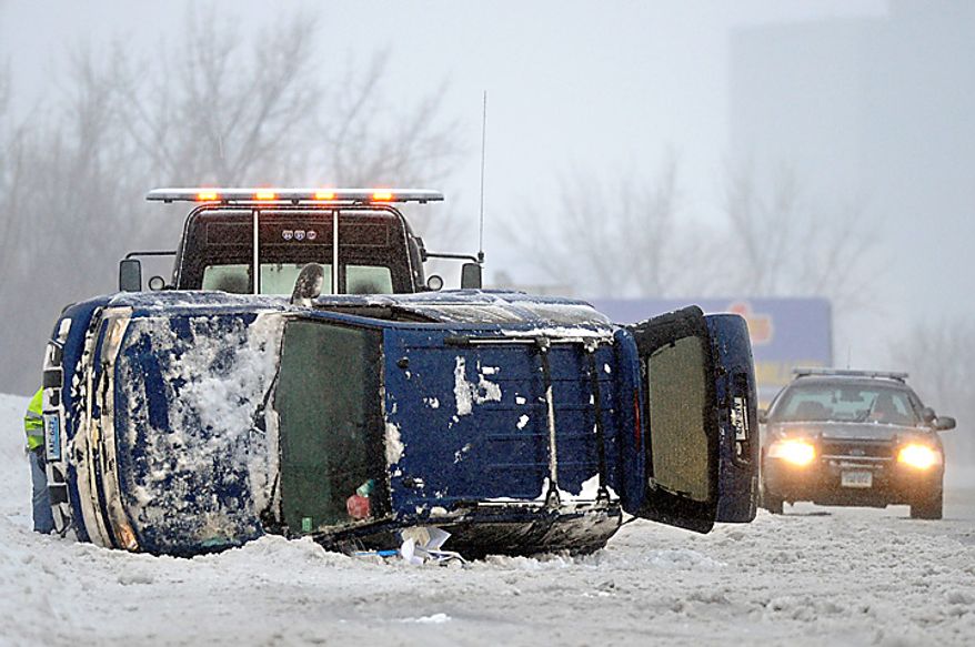 An SUV lies on its side after a rollover in sleeting conditions in Hartford, Conn., Wednesday, Feb. 2, 2011. (AP Photo/Jessica Hill)