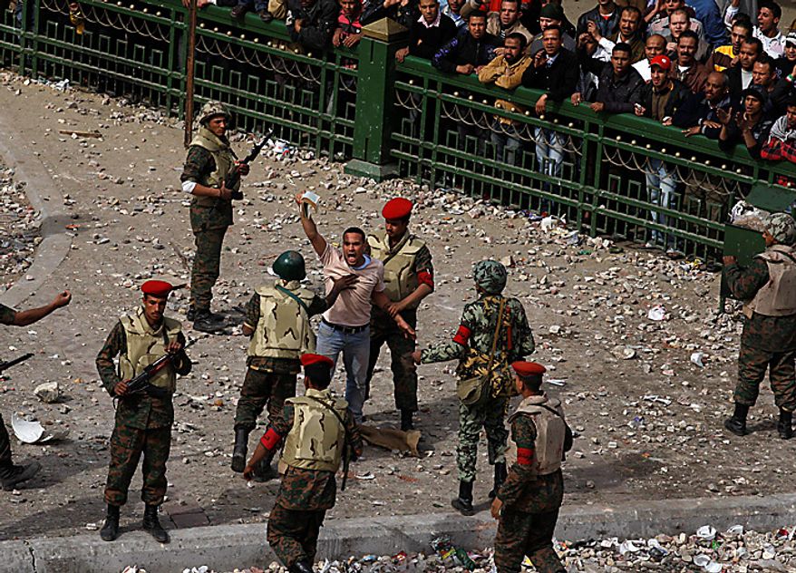 An Egyptian pro-government protester shouts as he is held back by army soldiers in downtown Cairo Thursday, Feb. 3, 2011. (AP Photo/Khalil Hamra)