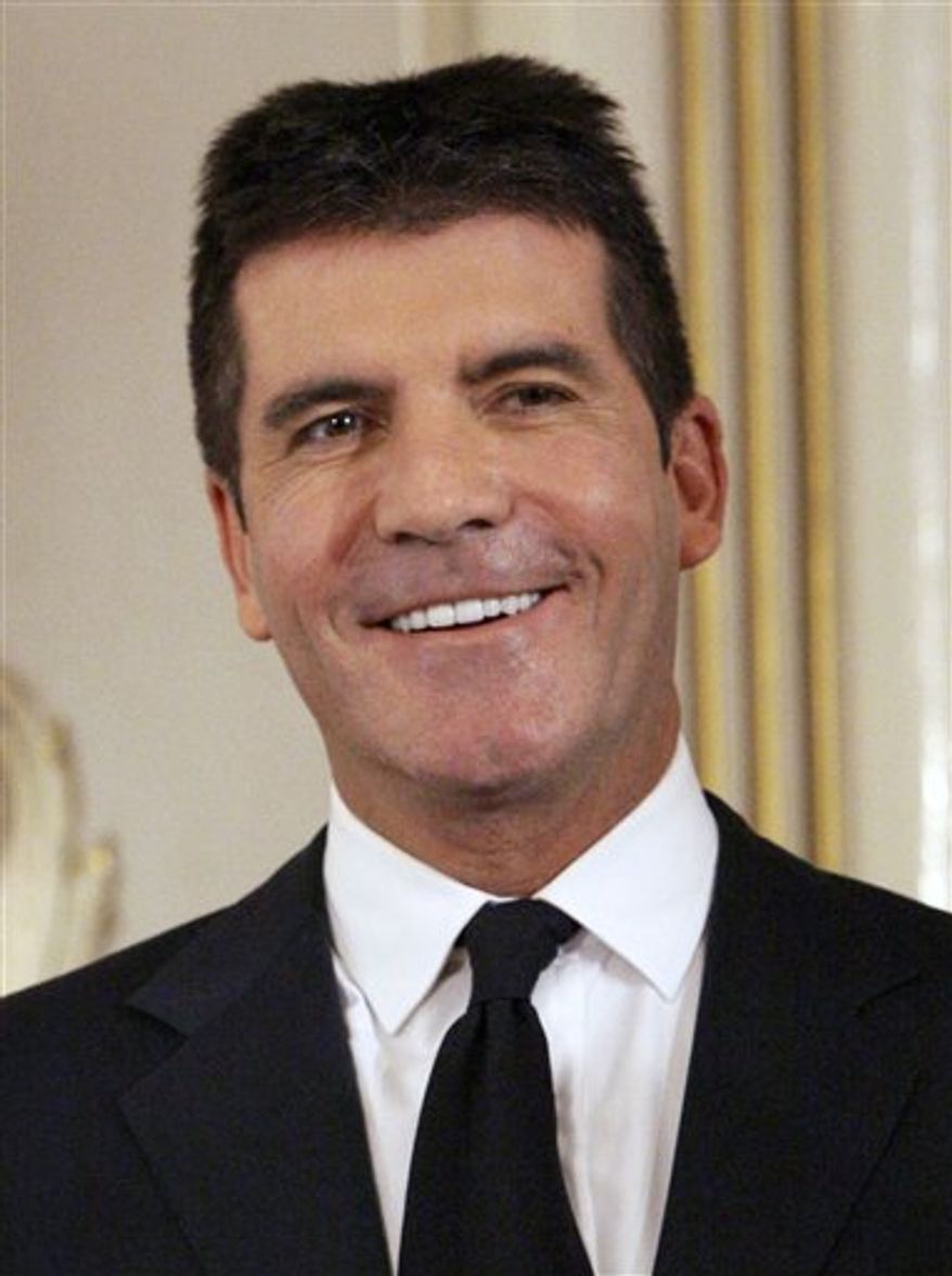 FILE- In this June 6, 2010 file photo, British music mogul Simon Cowell holds his honorary Bafta Award, during the British Academy Television Awards at the London Palladium in central London. (AP Photo/Joel Ryan, file)