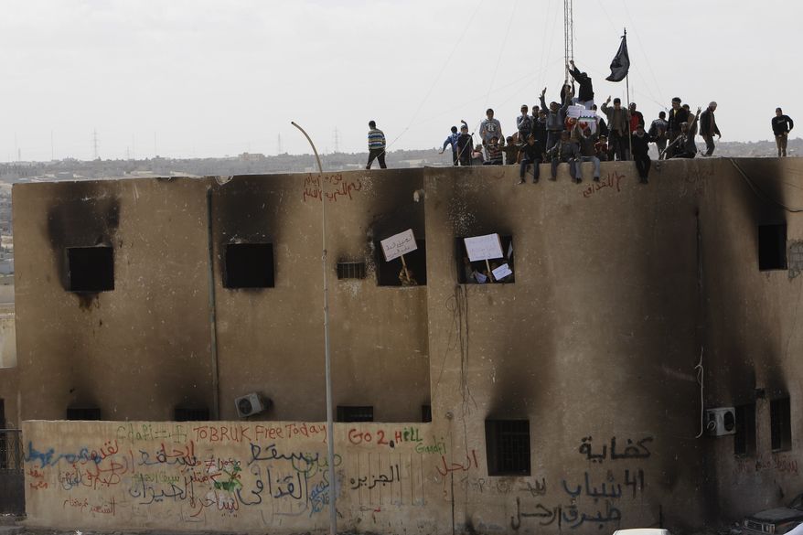 Libyan protesters stand on the rooftop of a burned police station during a demonstration against Moammar Gadhafi in Tobruk, Libya, on Wednesday, Feb. 23, 2011. Heavy gunfire broke out in Tripoli as forces loyal to Col. Gadhafi tightened their grip on the Libyan capital while anti-government protesters claimed control of many cities elsewhere and top government officials and diplomats turn against the longtime leader. (AP Photo/Hussein Malla)