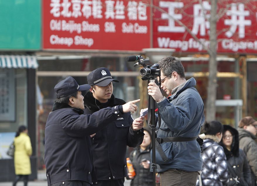 Chinese police ask an Associated Press cameraman to leave the area near the shopping street of Wangfujing in Beijing on Sunday, Feb. 27, 2011. Large numbers of police and the use of new tactics such as shrill whistles and street cleaners squelched any overt protests in China after calls for more peaceful gatherings modeled on recent democratic movements in the Middle East. (AP Photo/Andy Wong)
