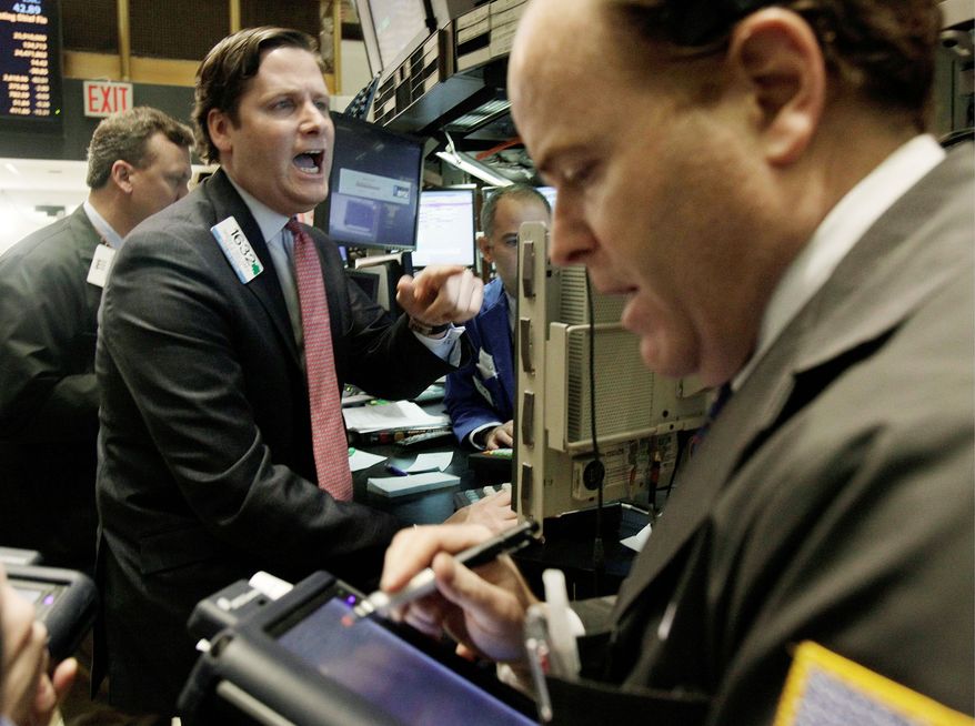 Specialist Gregg Maloney (center) gives prices as he works at his post on the floor of the New York Stock Exchange on Tuesday. (Associated Press)