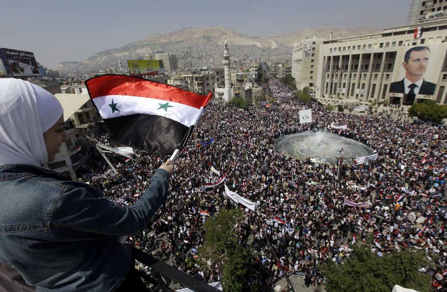 Pro-Syrian President Bashar Assad protester, waves Syrian flag as she looks to the crowed who demonstarte to show their support for their president, in Damascus, Syria, on Tuesday, March 29, 2011. Pledging allegiance for President Bashar Assad as he faces the biggest challenge to his 11-year rule, hundreds of thousands of Syrians gathered in a central Damascus square Tuesday, waving his pictures and chanting support. (AP Photo/Bassem Tellawi)