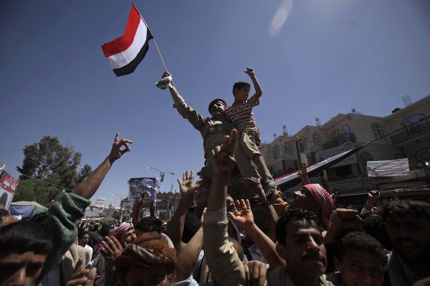A Yemeni army officer raised aloft by anti-government protesters holds a boy and waves a national flag during a demonstration demanding the resignation of Yemeni President Ali Abdullah Saleh in Sanaa, Yemen, on Monday, April 4, 2011.