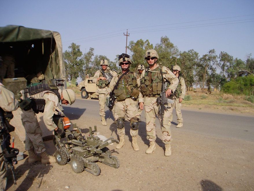 First Lieutenant Ungaro and Second Lieutenant Tilly standby as EOD preps a robot at an IED site in Iraq. (U.S. Army)
