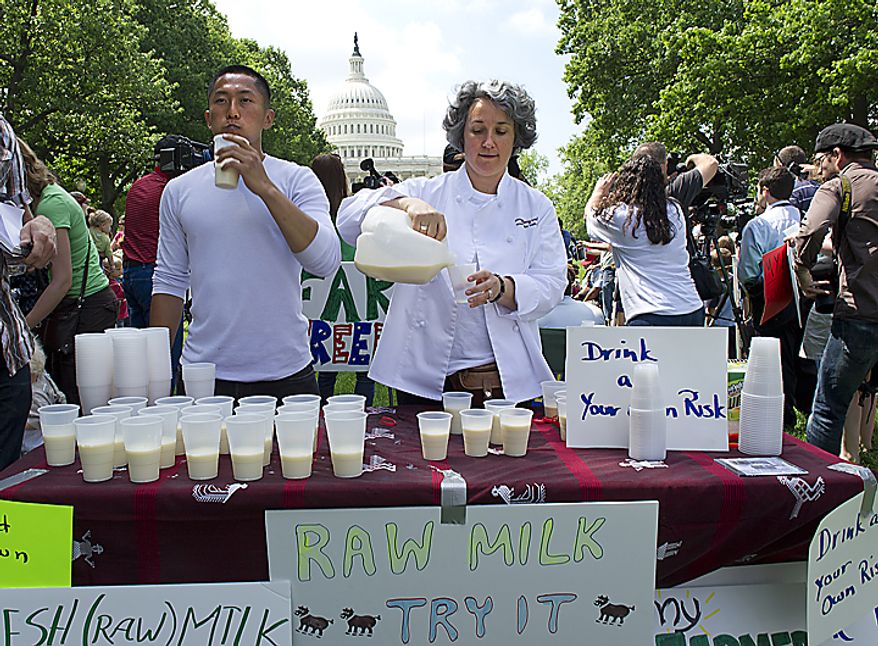 University of Maryland student Jake Lee, left, and real food chef and owner of Simply Being Well Monica Corrado, right, of Silver Spring, Md., serve fresh raw milk at a rally held by Grassfed on the Hill at Upper Senate Park in Washington, D.C., on Monday, May 16, 2011. The rally was held to protest the sting operation conducted by the FDA against Pennsylvania dairy farmer Dan Allgyer. (Barbara L. Salisbury/The Washington Times)