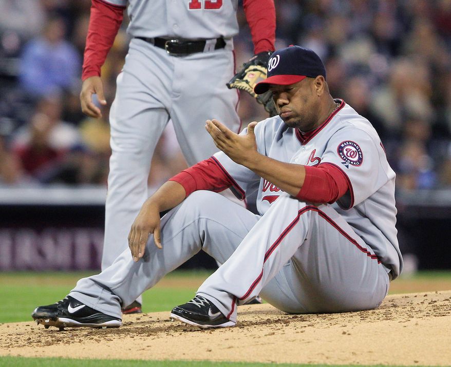 Nationals pitcher Livan Hernandez sits on the mound after being knocked down by a line drive that shot into his glove in a loss Thursday in San Diego. The righthander's ties to a drug dealer in Puerto Rico are under investigation. (Associated Press)