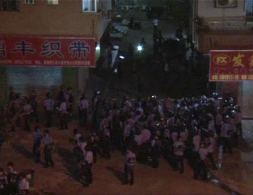 In an image made from video broadcast by Cable TV, helmeted anti-riot police try to arrest protesters in Xintang, in southern China's Guangdong Province, on Sunday, June 12, 2011. Demonstrators in the manufacturing hub torched emergency vehicles in an outburst of anger against police abuse of migrant workers, eyewitnesses said Monday. Sunday night's rioting followed three days of steadily growing unrest in the town. (AP Photo/Cable TV via Associated Press TV)