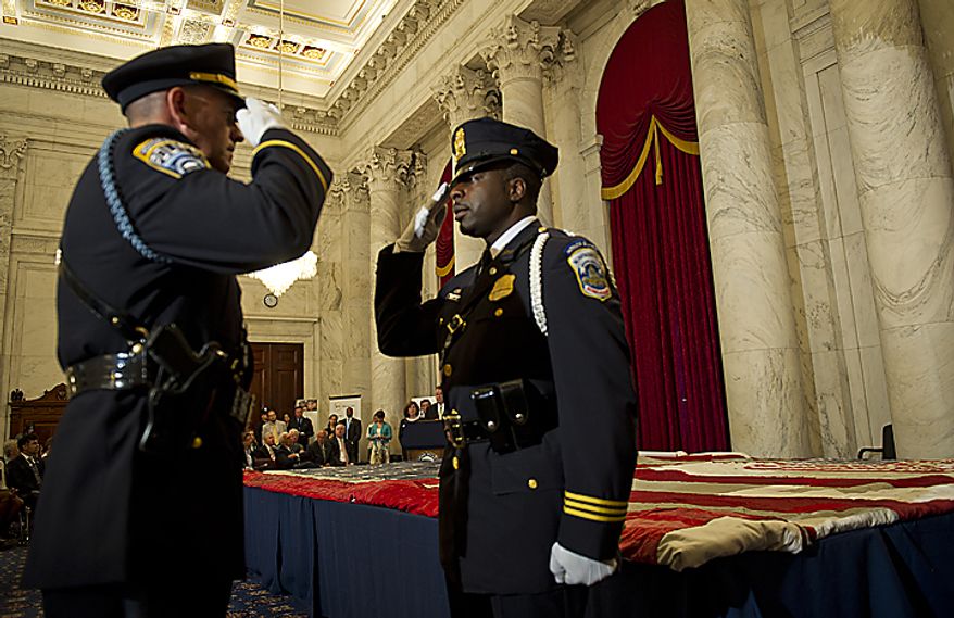 ** FILE ** Two U.S. Capitol Police officers exchange salutes as they change command while guarding the official 9/11 National flag during a stitching ceremony in the Kennedy Caucus Room in the Russell Senate Office Building in Washington, D.C., on Thursday, July 14, 2011. An American flag that was flying just south of the World Trade Center in New York City on Sept. 11, 2001, is making its way around the country and being stitched back together. (Barbara L. Salisbury/The Washington Times)
