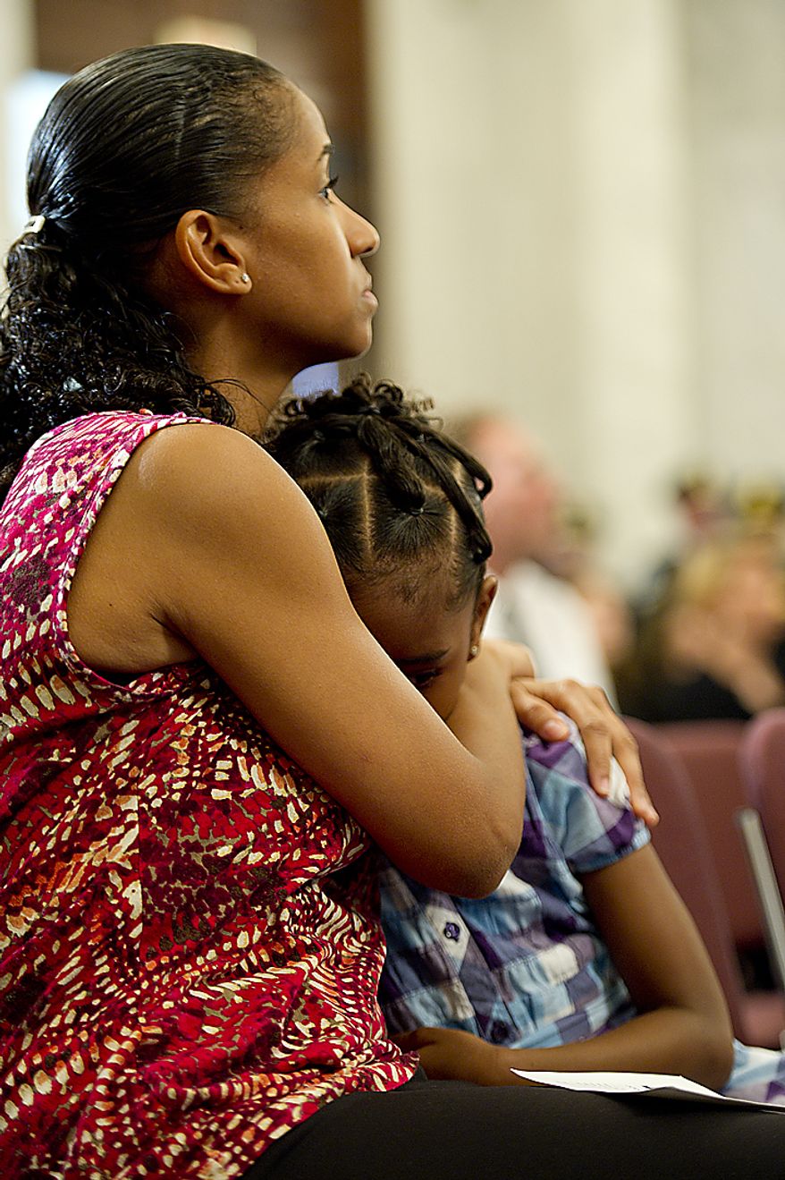 Miriam Carter of Ocoee, Fla., comforts her 6-year-old daughter Liana during the 9/11 National Flag Stitching Ceremony, held in the Kennedy Caucus Room in the Russell Senate Office Building in Washington, D.C., on Thursday, July 14, 2011. Carter's sister Maria Ramirez was killed in the Sept. 11 attack in New York City. An American flag that was flying just south of the World Trade Center in New York City on Sept. 11, 2001 is making its way around the country and being stitched back together. The goal is to have the flag completed by this Sept. 11, in time for the 10th memorial. The finished flag will be on display at the official 9/11 Memorial in New York City. (Barbara L. Salisbury/The Washington Times)