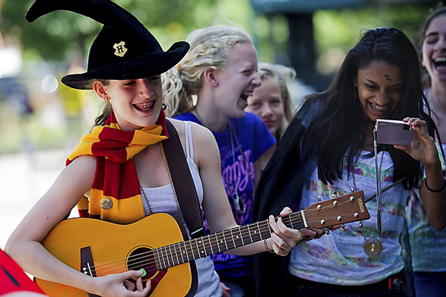 At left, Sofia Roma, 14, of the District, plays and sings "Goin' Back to Hogwarts," a song from "A Very Potter Musical," while her and her friends wait for the midnight start of the final Harry Potter movie, near the Uptown Theater along Connecticut Ave. in Cleveland Park, in Washington, D.C., Thursday, July 14, 2011. "The best part of the waiting in line experience is meeting all the other fans," said Roma. (Drew Angerer/The Washington Times)