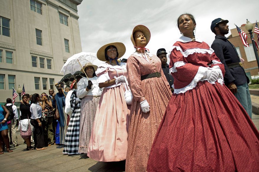 Members of FREED, Female Re-enactors of Distinction, led by Dorothy Stevens (top, far right) and Judy Williams (second from right) get ready to move across Vermont Avenue in Northwest for the reception at the reopening of the African American Civil War Museum on Monday. Soldier re-enactors were part of the program. The District government provided $5 million to help the museum move into the former Grimke School to allow it to expand. Frank Smith, director and founder of the museum, cuts the ribbon to the entrance (above). (Photographs by Drew Angerer/The Washington Times)